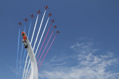The Red Arrows fly past the Goodwood sculpture. Note the sun!