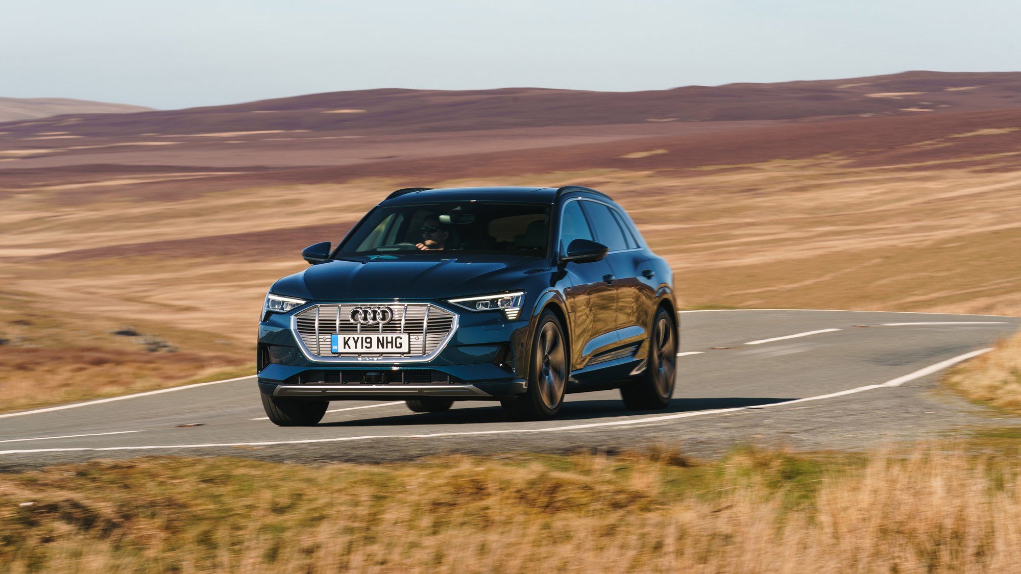 Here it is, the most important Audi in decades; the all-electric e-Tron SUV. The first step of a ascendance from nitrogen dioxide sinner to aspiring zero-emission saint, the handsome-looking EV is just the beginning for Ingolstadt’s electric plans. After this, there’ll be a flurry of EVs from the four rings, with a Sportback and a J1-based e-Tron GT Coupe following soon after.   Available to order now with the first UK deliveries only just rolling out of the factory, the new 2019 Audi e-Tron has a certified 241-mile electric range, and promises trademark Audi performance, four-wheel drive, the usual quality interior – and cleaner guts.   We were there when the e-Tron was first revealed in San Francisco, and we’ve driven it on the worldwide launch, too. It can tick all the boxes in Dubai – but can the e-Tron do it on a cold day in North Yorkshire? Keep reading for our full UK review.   ***What's the UK-spec Audi e-Tron like inside?   Slip into the e-Tron, and it fits Audi’s tagline for the car perfectly. ‘EV goes Audi’ is the ethos inside and out, and that means the e-Tron’s cabin could be in any Q car.   The touchscreen-heavy cabin invites you to swipe and pinch just like the A8 – and even the steering wheel isn’t particularly EV-alike. The cruise control switches are lifted straight from the TTS we’ve driven here, and there are paddles, too – which we’ll get to later.  In fact, it’s the only the transmission where the e-Tron dares to be different – and that’s because it doesn’t have one. Instead, the area between the passenger and driver is full of storage space with cubby holes, cup-holders and a wireless phone charger all packed into a rather bulky, plastic frame. We’d rather the empty space.   Still the e-Tron does differentiate itself with an unusual thumb-flicking drive selector. Mounted under a hand rest, it’s pleasingly tactile - and is clicked forward and back by your thumb and index finger. It’s a small thing, but it’s something you’ll notice every time you drive.   ****Well. how does the e-Tron actually drive, then?   Click into Drive, gingerly apply the throttle – this car won’t creep forward like a Tesla – and the firmness of the pedal is the first big surprise. The e-Tron is a 2.5-tonne SUV, with a right pedal more McLaren-like than you’d think. It quietly makes you less blunt with your inputs, and in S mode, it gives the car a sportier feel, too. It’s a win-win.   Flex the power of the e-Tron with your foot to the floor, and it accelerates in a progressive, but ultimately physics-bending way, and eerie silence is quickly overtaken by wind and road noise.   ****What’s it like to drive in the UK?   That instant torque makes entering  roundabouts easier, allowing you to more safely dart into gaps, and it makes overtaking a simple, effortless experience, too. Passing another car is as simple as checking the oncoming traffic, easing on the power and slotting in front. No hesitant kickdowns, no noise –  just a whoosh. Seamless.   As for the ride? Even on North Yorkshire’s roughest roads, the e-Tron delivers a composed, and planted ride comfort regardless of the setting you’re on. Flick into Comfort using the very familiar Drive Select button, and you’ll find the throttle response rounded off, lighter steering and the bumps smoothed out.   Move over to Sport; power response is instant, the wheel weights up and you feel those nooks and crannies in the surface of the tarmac a little more. Body roll, while minimal in Comfort, is further reduced in Sport, and makes you want to push the 2.5-tonne SUV just a bit harder.  Braking uses both discs and energy-saving regen, seamlessly switching between the two depending on your application. It works very well, with little jolting or juddering as the system switches between the two.  On motorways, you’ll find the e-Tron like any other car – except for its effortless ability to overtake. Wind noise and tyre noise are even more apparent without the hum of combustion, though, and you’ll notice whistling around around the wing mirrors and A-pillars.  We were driving a conventionally mirrored model; it’ll be interesting to see if the lower-dragged, electric-cameras have a big impact on wind noise. And some more on the e-Trons webcams. They’re actually legal in the UK, and they’re able to slightly enhance the image they receive, so you actually see more with them in low-light conditions.    They’re standard with the £82,270 Launch edition e-Tron - not the entry-level £71,520 car. If you want them on anything other than launch-spec, the cameras will set you back £1250.   And what about those paddles? Look around the cabin, and you won’t find a B-mode for increased regen; instead, Audi’s mapped that function to paddles behind the wheel. Tap the + paddle to increase resistance and energy recovery, and pull the – paddle for less. In some ways, it makes sense to have it behind the wheel;  it’s a form of engine braking or ‘gear’ use – but it’ll take  time to learn and use it intelligently.   ****Newton still wins  Of course, the new Audi e-Tron isn’t a sports car, and when you’re doing anything other than accelerating in a straight line , it can’t really repeal the laws of physics. Body roll isn’t a large factor, but, the height and the weight of the car is more apparent on corner entry. It’s very much the same experience you get in something like a Tesla Model X; it’s a supercar when going straight ahead, but you’re acutely aware of every kg of its weight when you’re doing anything else.   ****UK verdict?   In many ways, the e-Tron is just like any other Audi, inside and out - but that’s what makes it exciting. It’s an SUV you can imagine slotting easily into your everyday life, with more charging options, and packages easing you over the ever-shrinking hurdles of EV ownership. 