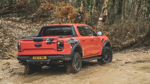 Ford Ranger Raptor (2023) review: rear three quarter cornering on dirt, leaving water splash, orange paint