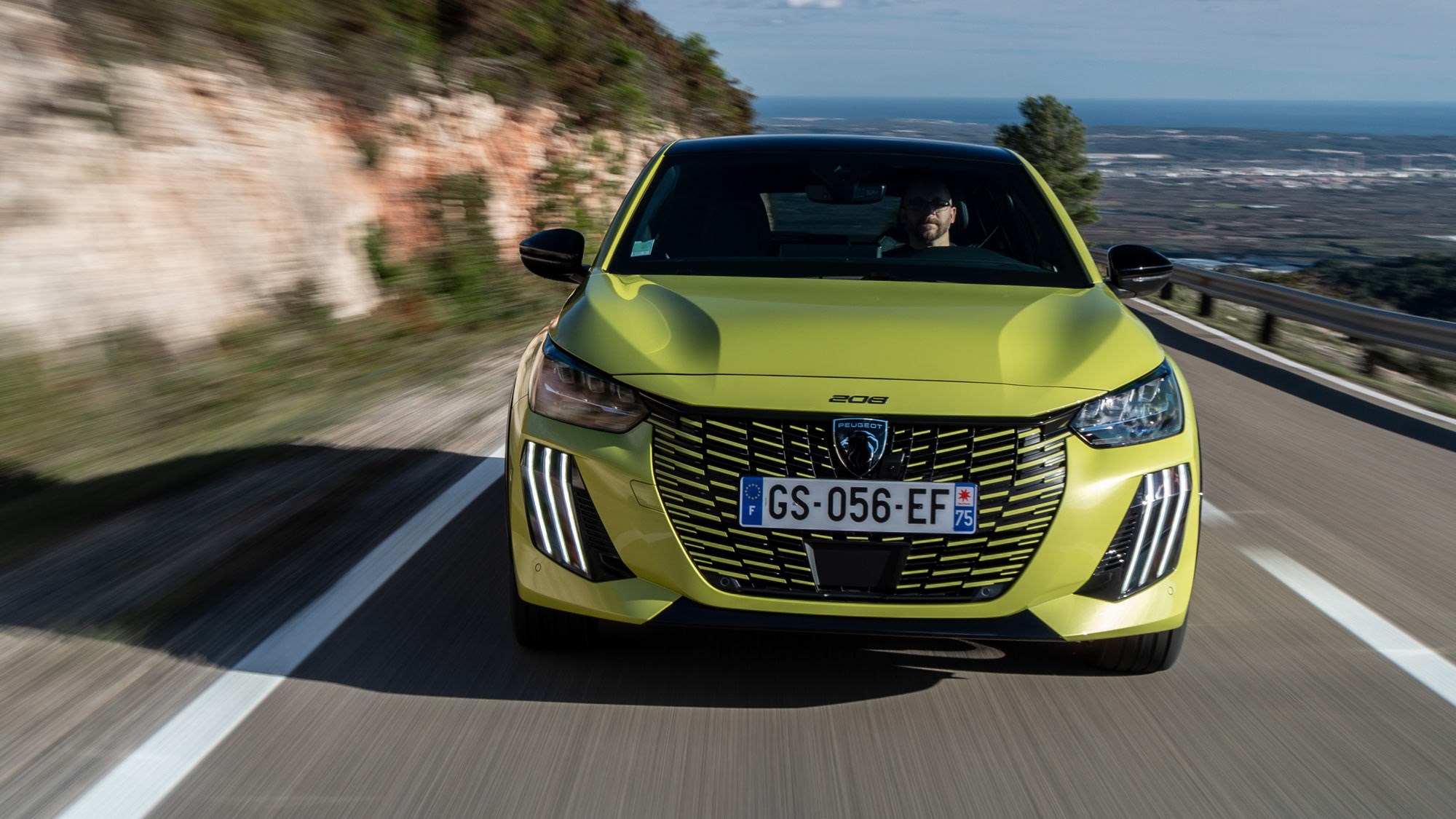 Peugeot E-208 review - dead-on front, driving, yellow