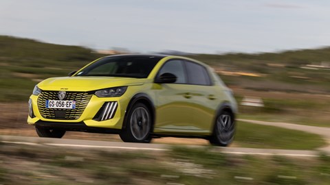 Peugeot E-208 review - front, yellow, driving round corner