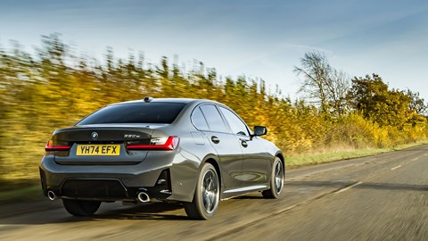 BMW 330e (2024) review: rear three quarter driving, grey paint