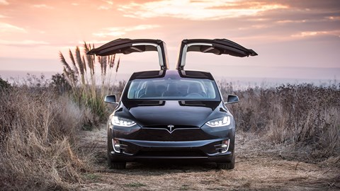Tesla Model X with Falcon Wing doors open against a sunset