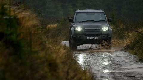 Land Rover Defender V8: front three quarter off-roading, muddy trail, black car