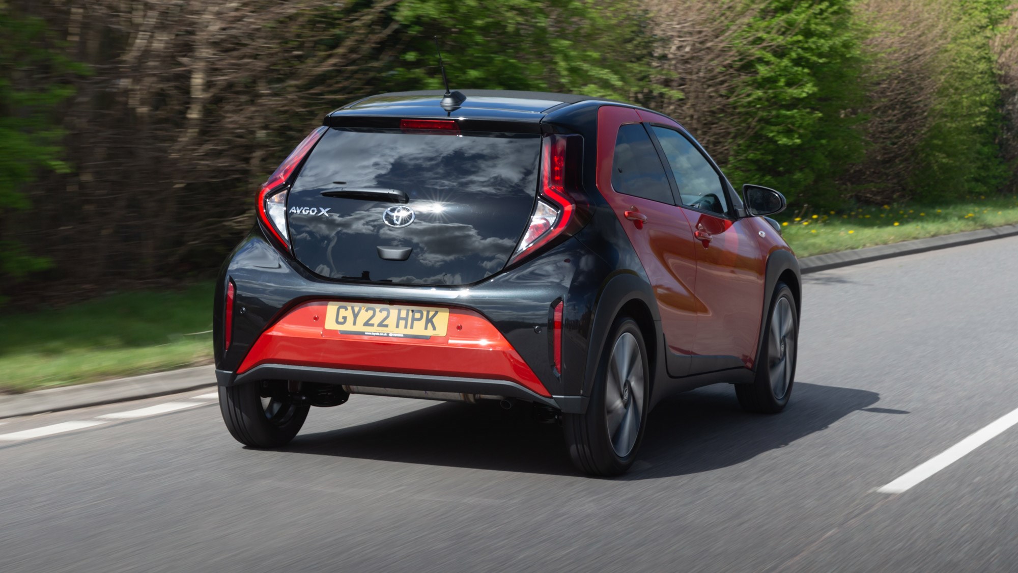 Toyota Aygo X review, rear view, orange, driving