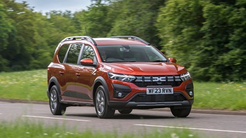 Dacia Jogger Hybrid (2023): front three quarter driving, country lane, orange car