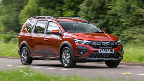 Dacia Jogger Hybrid (2023): front three quarter cornering, country lane, orange car