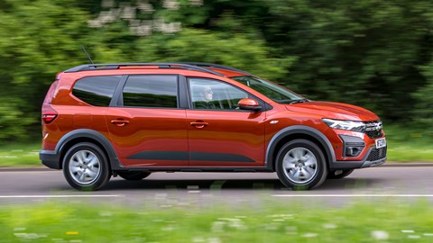 Dacia Jogger Hybrid (2023): side view driving, country lane, orange car