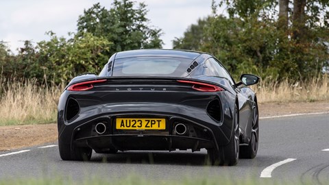 Lotus Emira (2023): rear three quarter cornering, black paint, country lane