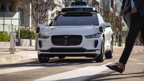 Driving shot of Waymo partnered Jaguar I-Pace in beta testing pilot, stopped at crossing for pedestrian
