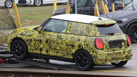 2023 Mini hatch spy shots - rear view, yellow camo, white roof, black wheels, being loaded on truck