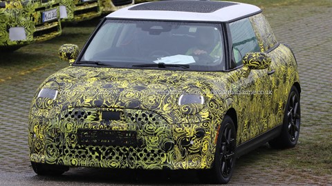 2023 Mini hatchback spy photos - front view, yellow camo, white roof with sunroof, black wheels