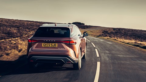Lexus RX 450h+ review: rear three quarter tracking shot, bronze car, country road