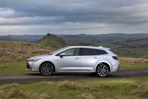 Image of a silver Toyota Corolla Touring Sports stood static with Peak District in background, viewed from the left side