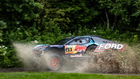 Image of Ford Raptor T1+ Dakar Rally car driving through large puddle, side view