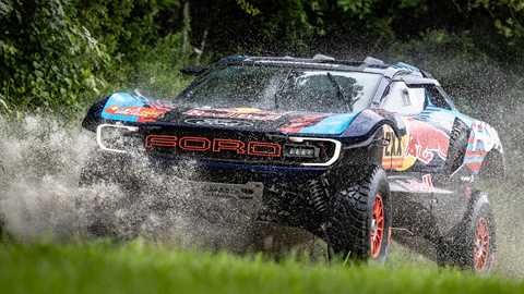 Image of Ford Raptor T1+ Dakar Rally car driving through large puddle, front three-quarters view