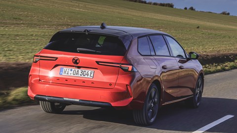 Vauxhall Astra Sports Tourer Electric (2023) review: rear three quarter driving, British country lane, high angle, red paint