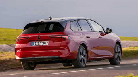 Vauxhall Astra Sports Tourer Electric (2023) review: rear three quarter driving, low angle, British country lane, red paint