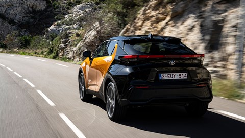 Toyota C-HR PHEV (2024) review: rear three quarter driving, orange and black paint, French roads