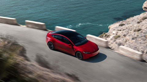 Tesla Model 3 Performance: front three quarter driving, high angle, red paint