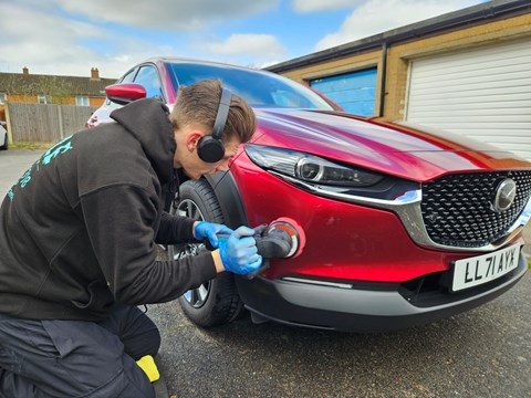 A red car being polished by a detailer