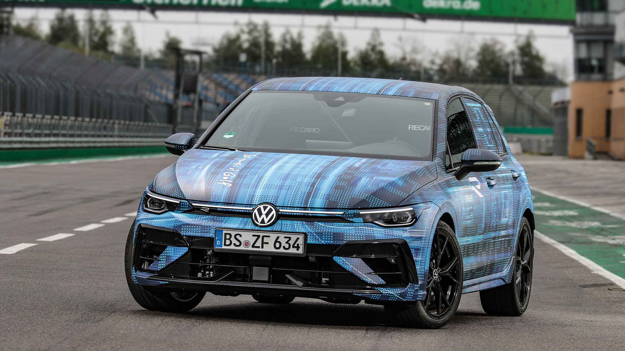 Volkswagen Golf R prototype review: front three quarter static, low angle, on a racetrack, camo wrap