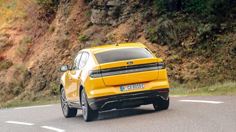 Ford Capri (2024) review: rear three quarter cornering, yellow paint, hill in background