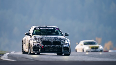 Image of a BMW M2 Racing, in testing livery, on track, going down a straight