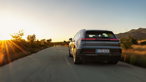 The back of a Porsche on the road, with the sun setting.