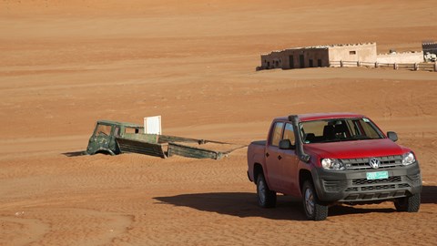 VW Amarok and old buried truck at 1000 Nights desert camp in Oman