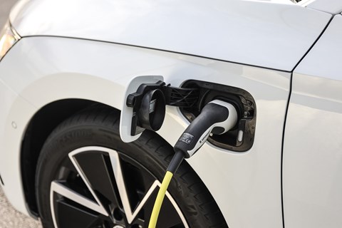 Plug-in hybrid plugged into electric car charger, vehicle is white, charging lead is yellow