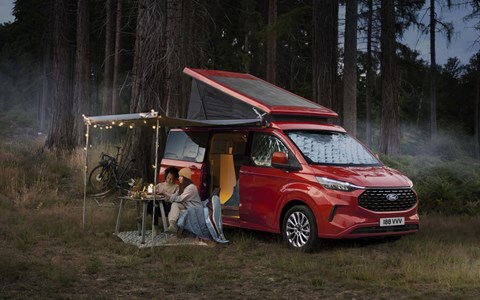 Image of a red Ford Transit Custom Nugget pitched up in a wood