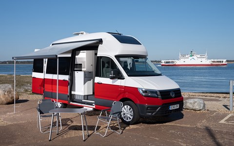 Image of a red/white Volkswagen Grand California pitched up on a dockside