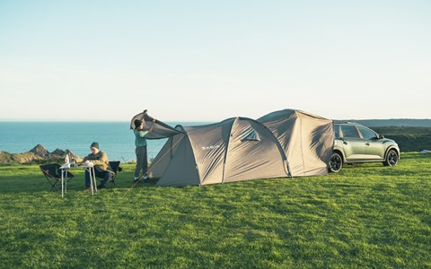 Image of a green Dacia Jogger Sleep Pack Ultimate pitched up on a clifftop