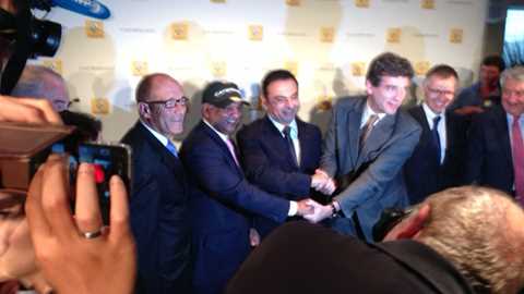 Caterham owner Tony Fernandes (wearing cap) and Renault chief Carlos Ghosn (suit to his right) shake on the creation of the new Alpine-Caterham joint venture